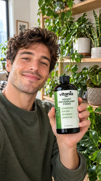 Customer holding Vitania Instant Houseplant Food in front of his plant shelf